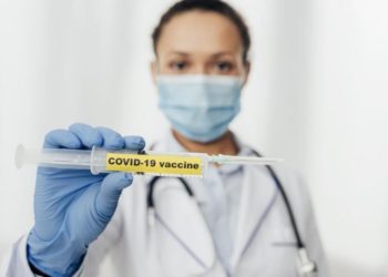 Doctor holding out the COVID-19 Vaccine